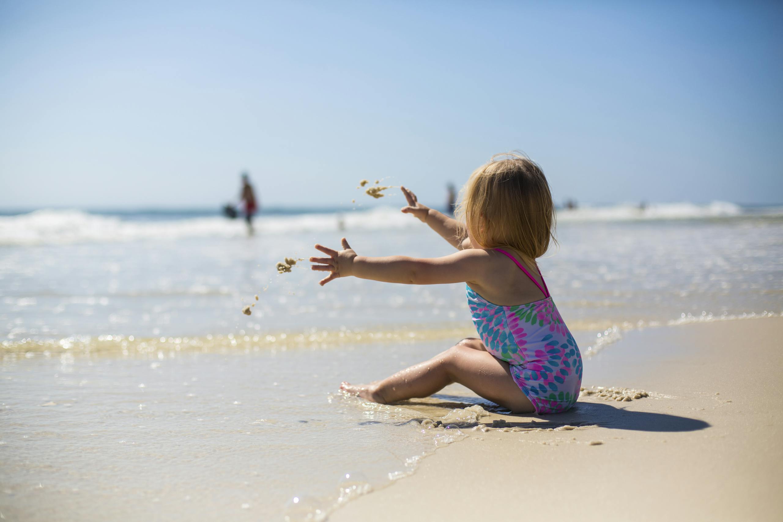 A toddler enjoying the sunny beach while playing with sand, capturing a moment of pure joy and innocence.